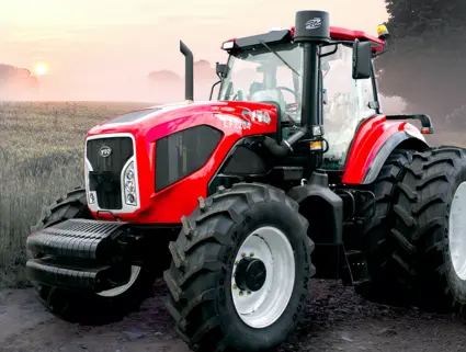 Beau tracteur agricole de couleur rouge vif sur un chemin de ferme